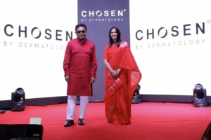 A.R. Rahman and Dr. Renita Rajan standing on stage with CHOSEN by Dermatology branding backdrop, both wearing traditional attire at the HIFIVE Conclave