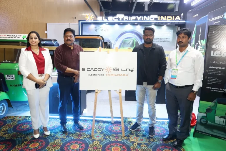 E DADDY team and dignitaries unveil the “Electrifying Tamil Nadu” campaign at EV India Expo 2025, standing beside a display board and retrofitted green auto rickshaws at their exhibition booth.