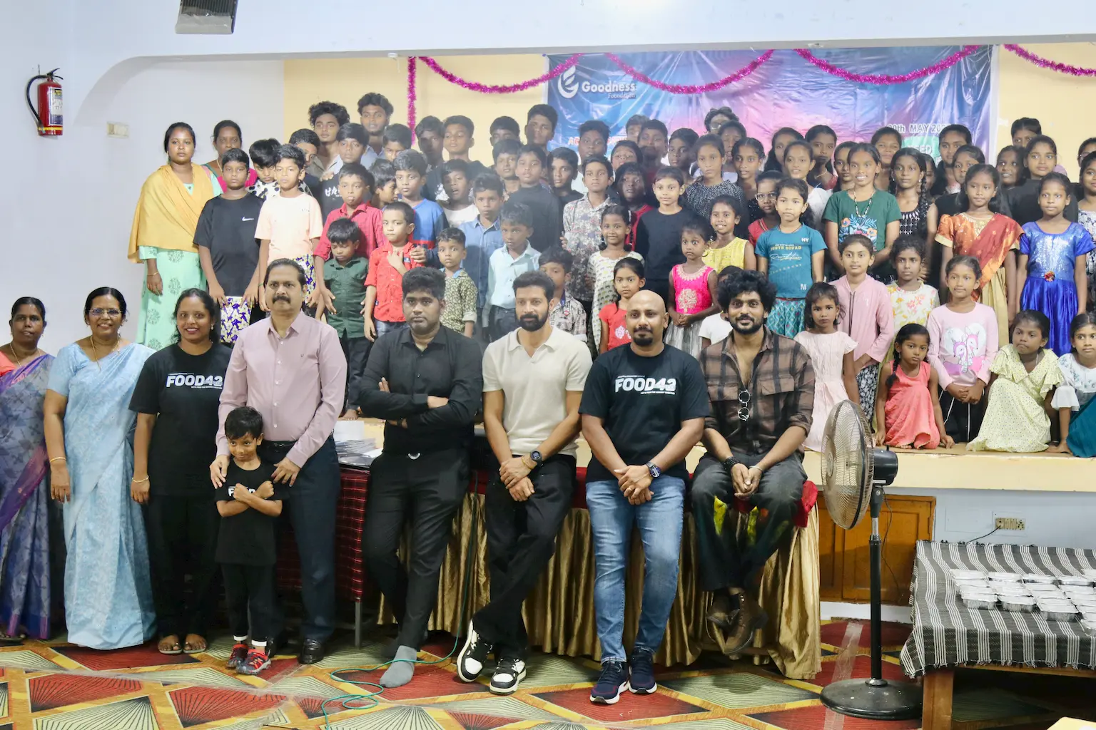 Food42 – 2025 campaign launch event showing actors Santhosh Prathap and Raanav, Goodness Foundation team members, and dozens of children from the community gathered together symbolizing the collective effort to combat hunger in India.