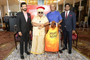 Padma Shri Dr. Chef Damu in traditional attire with Chef Sheetharam Prasad and team at the launch of Thalaivan Virunthu 3.0, Grand Chennai by GRT Hotels, with a branded apron on display