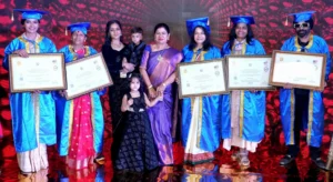 Sanchita Shetty, Rakhi Shah, Tara Kerkar, and other recipients pose with their Honorary Doctorate certificates at the award ceremony in Coimbatore, wearing blue academic gowns and caps, joined by guests and children.