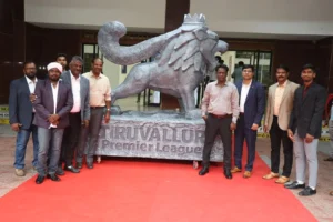 Officials and dignitaries posing beside the Tiruvallur Premier League lion mascot statue during the TPL 3.0 launch event at Mayor Radhakrishnan Stadium.