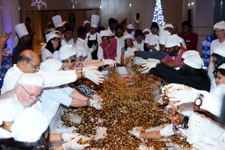 Guests and hotel staff joyfully mixing dried fruits together during the Grand Madurai Christmas Cake Mixing Ceremony.