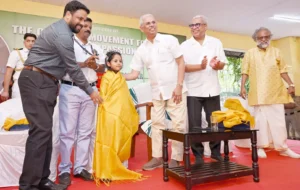 Kerala Governor Rajendra Vishwanath Arlekar felicitating young environmentalist Roohi Mohazzab during the inauguration of Roohi’s Tree Bank Nursery project in Kozhikode, as dignitaries applaud on stage.